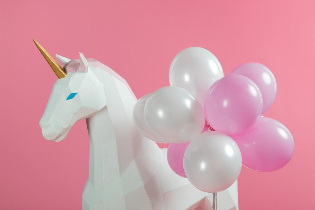 Party decoration with unicorn and balloons isolated on pink